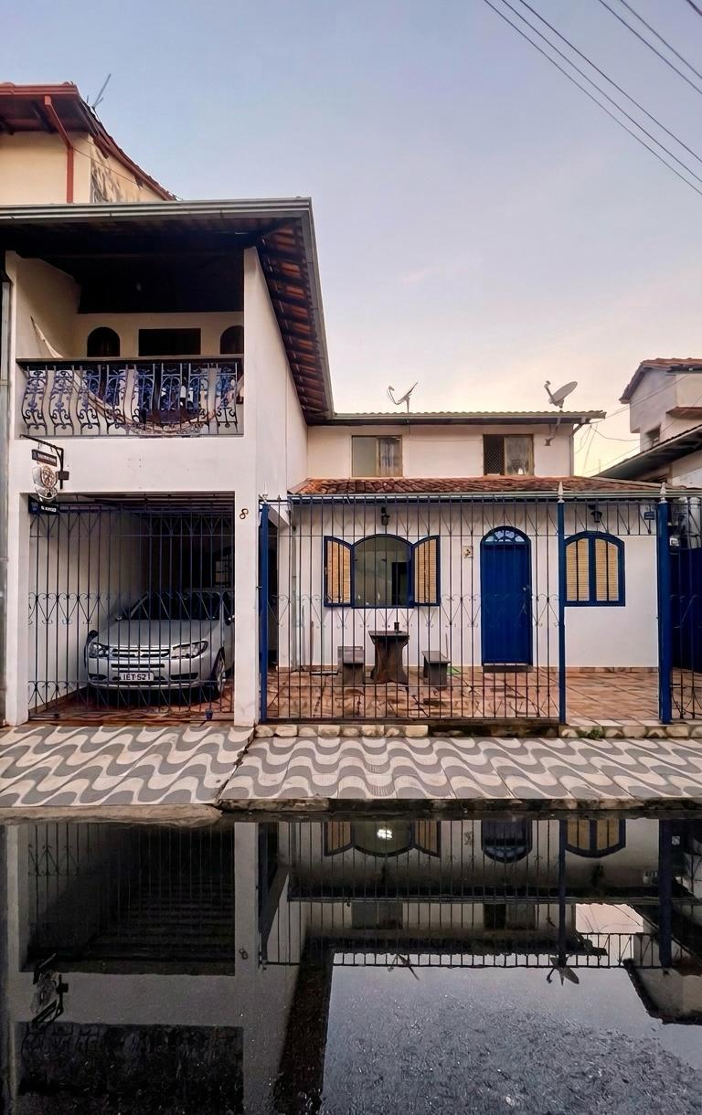 Fachada azul e branca da casa com calçada de pedra portuguesa