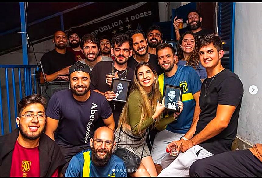 Turma reunida sob a bandeira com os retratos dos antigos