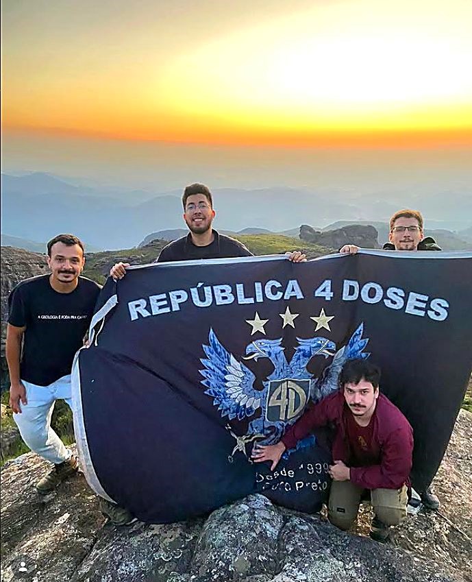 Moradores no alto da serra com a bandeira ao pôr do sol