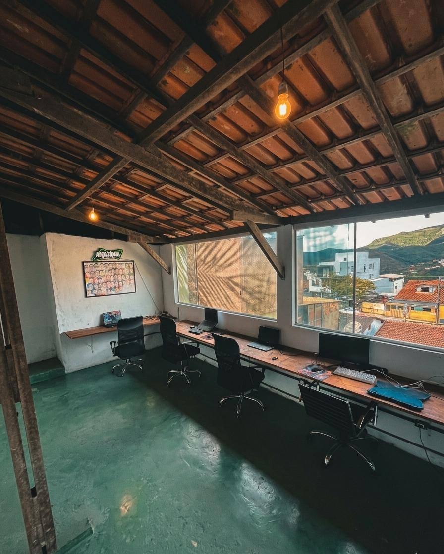 Sala de estudos com mesa longa, computadores e janela com vista para as montanhas