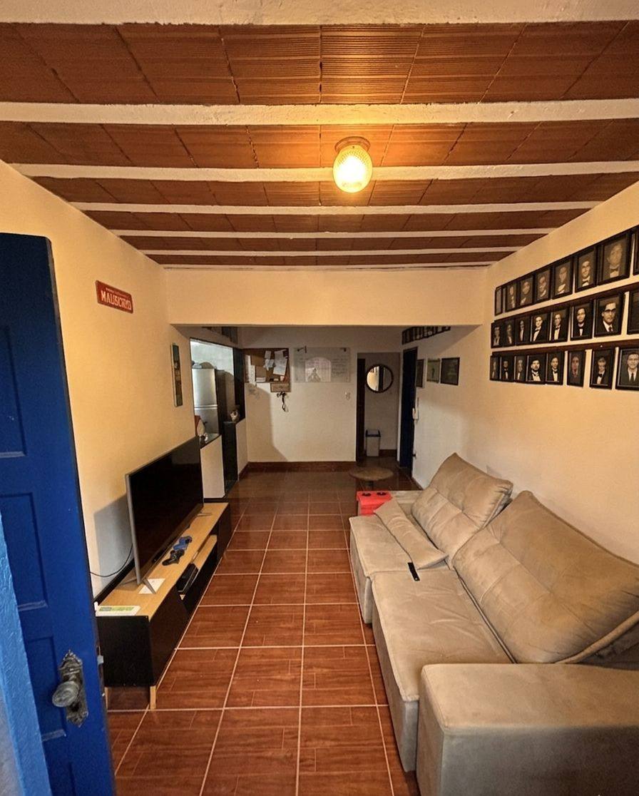Sala de estar com sofá e parede com retratos dos ex-moradores